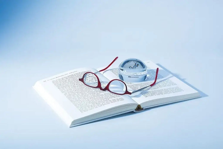 Brille und eine Hellfeldlupe auf einem Buch